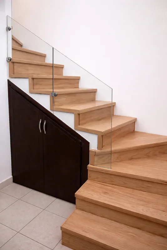 Escalera de madera de encino con barandal de cristal y closet bajo escalera en Hermosillo